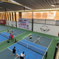 Indoor pickleball court with players on a blue court