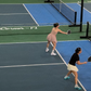 Two people playing tennis on a blue court with advertisements in the background.