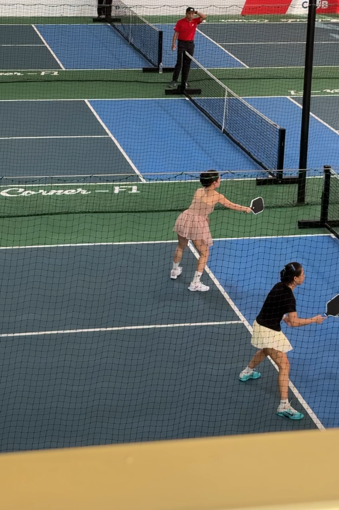 Two people playing tennis on a blue court with advertisements in the background.