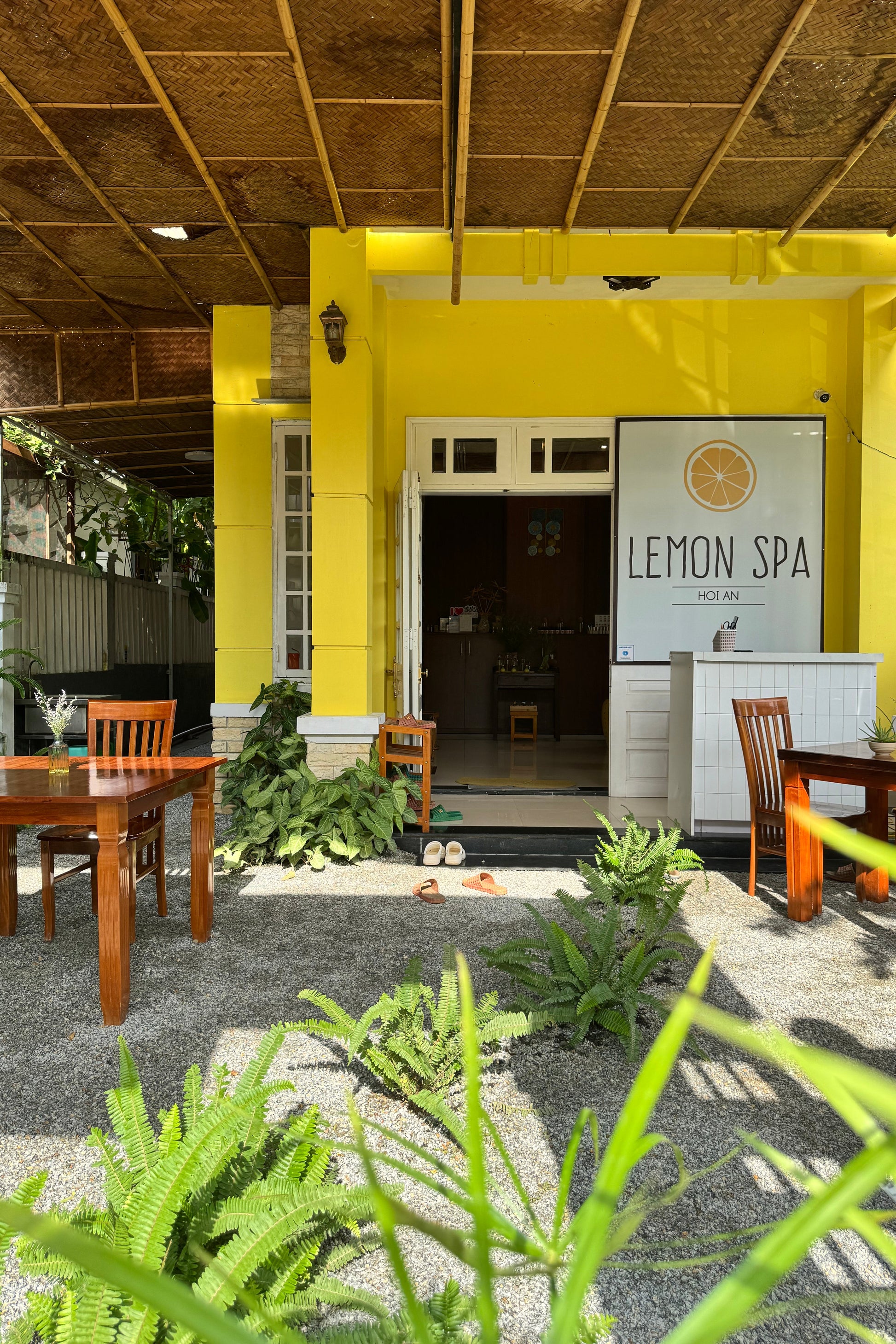 Yellow building with 'Lemon Spa' sign, surrounded by plants and chairs.