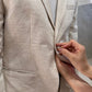 Person adjusting a beige linen garment with a neutral background
