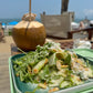 Salad in a green container with a blurred outdoor background