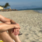 Man sitting on a beach towel under a blue sky