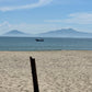 Fishing boat passing by the beach with a clear sky and islands in the background