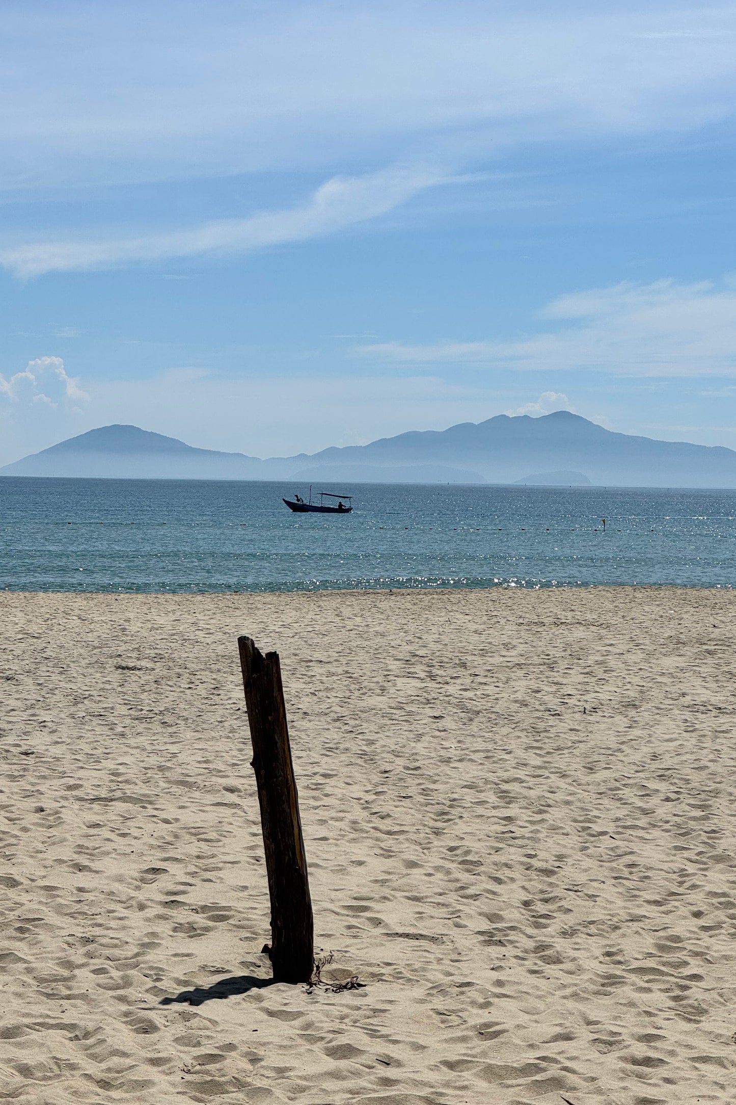 Fishing boat passing by the beach with a clear sky and islands in the background