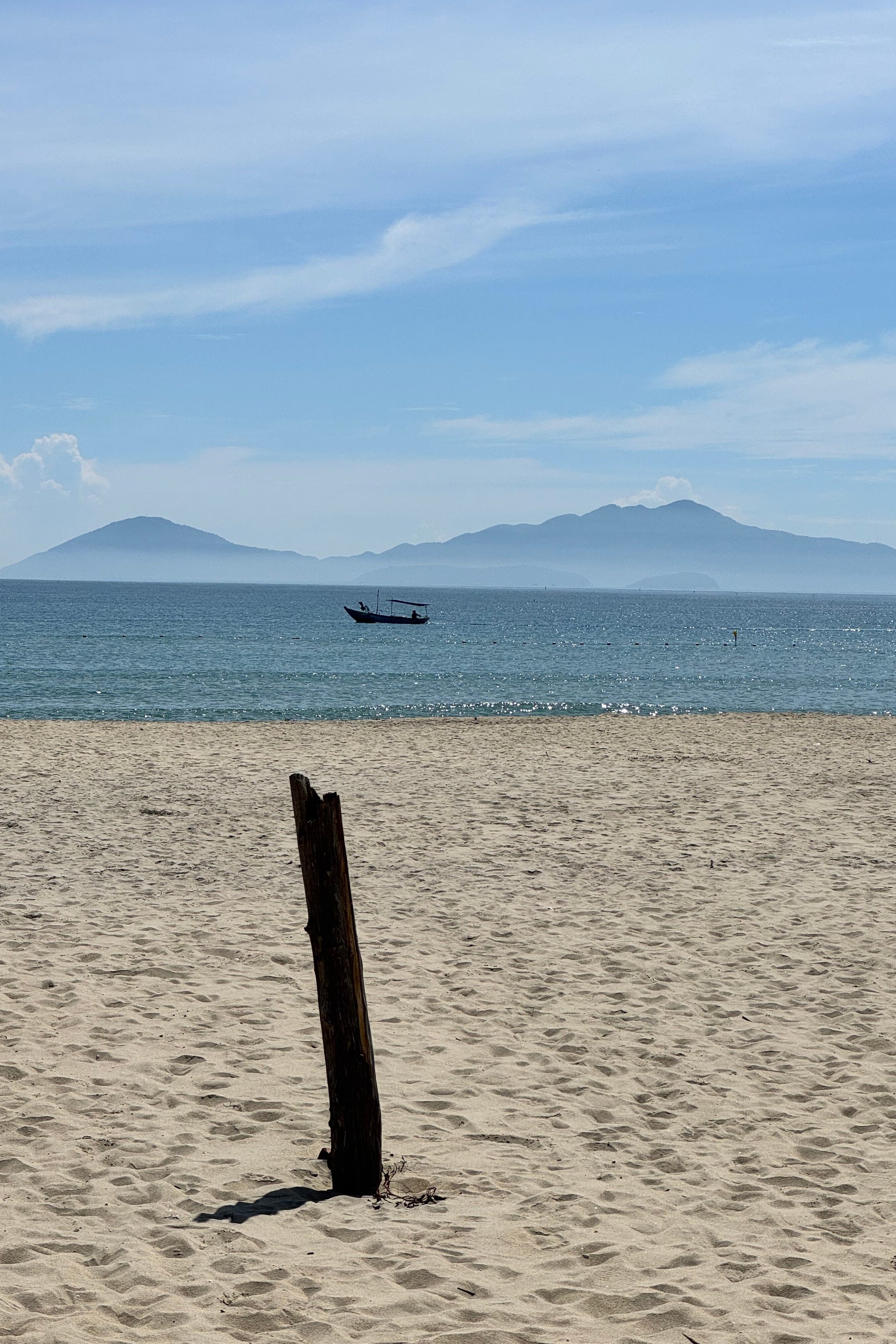 Fishing boat passing by the beach with a clear sky and islands in the background