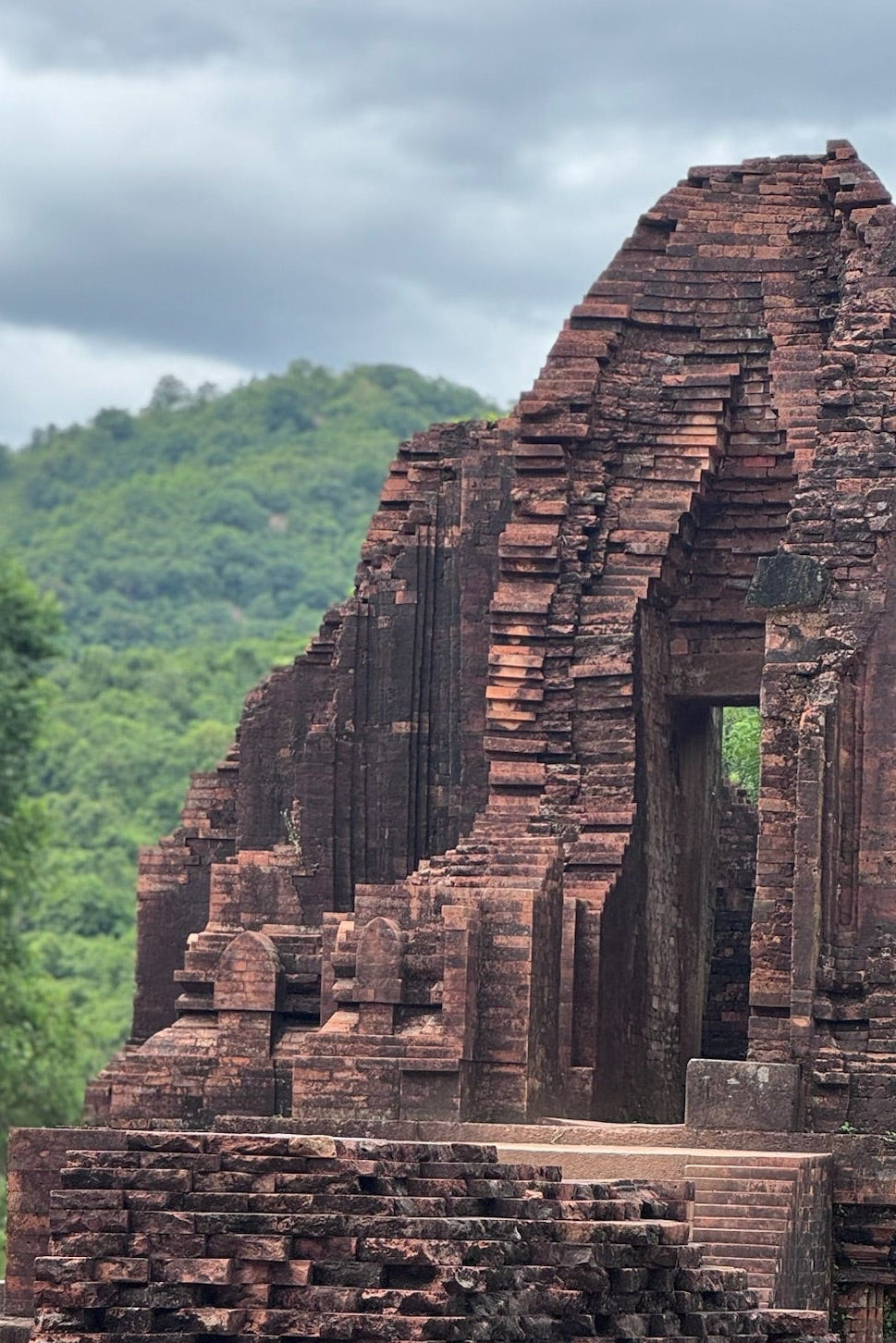 Person standing on ancient brick ruins with greenery in the background